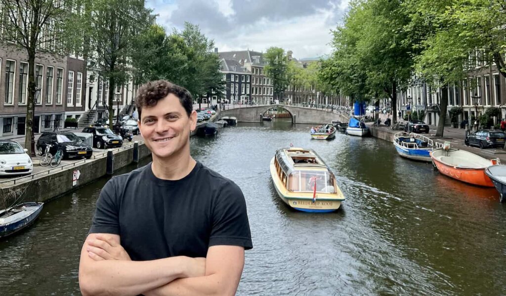 Nomadic Matt posing near a historic canal in sunny Amsterdam, Netherlands