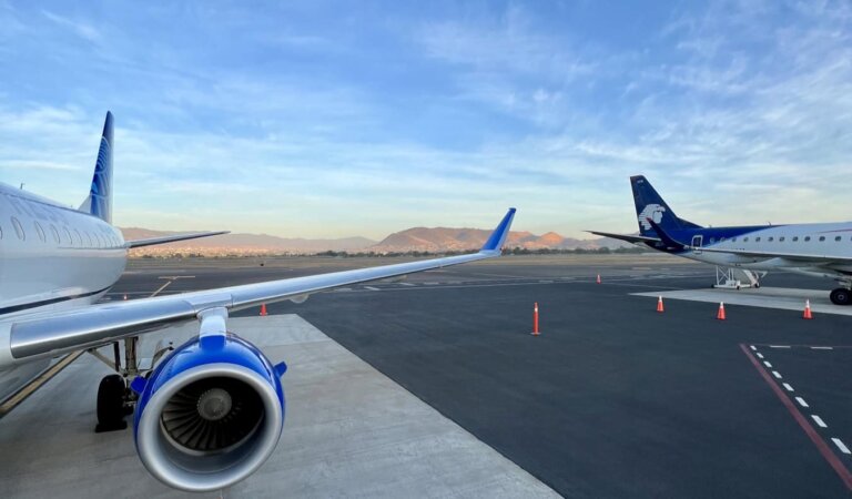 Two airplanes parked at an airport ready for travelers to board them