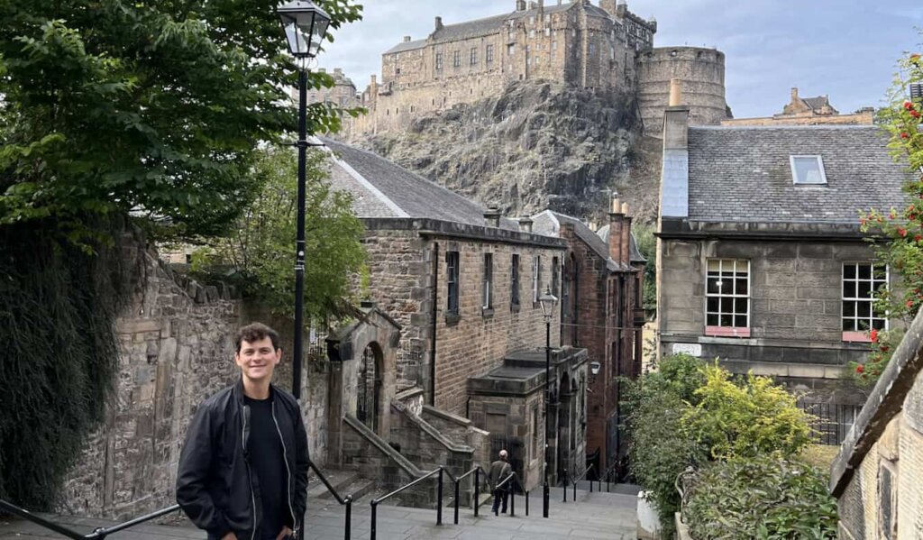 Nomadic Matt posing for a photo near the castle in the Old Town of Edinburgh, Scotland