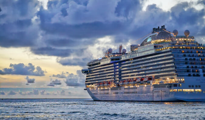 A large cruise ship sailing into the cloudy sunset