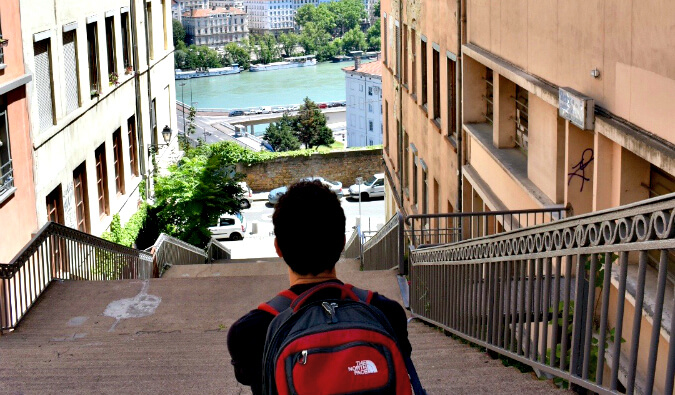 Nomadic Matt sitting at the top of steps looking down towards a river in the background