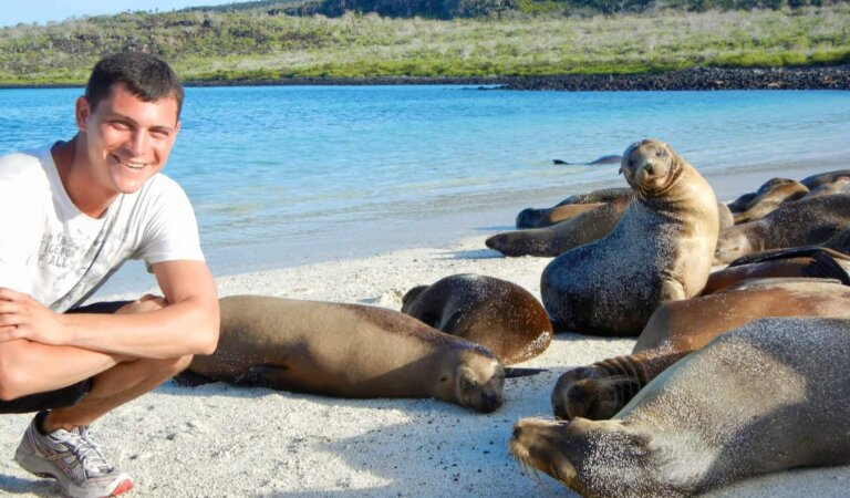 Nomadic Matt on the beach in the Galapagos near a group of sleeping sea lions
