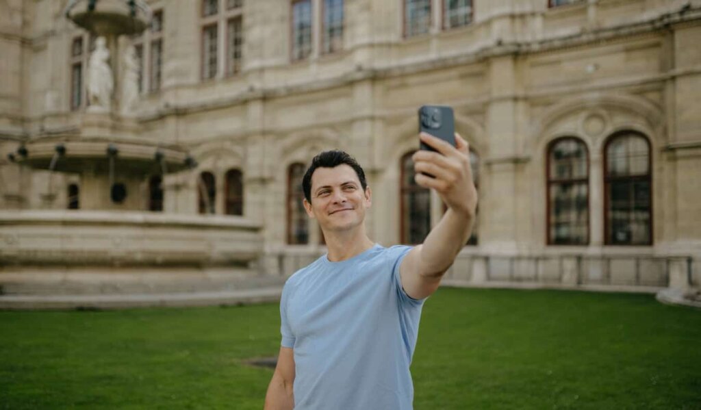 Nomadic Matt taking a selfie in front of a historic building and fountain