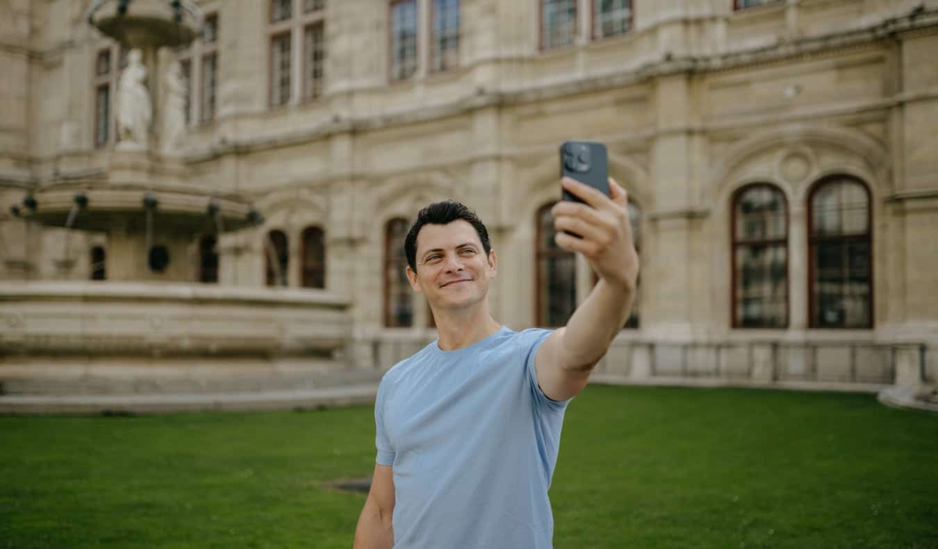 Nomadic Matt taking a selfie in front of a historic building and fountain