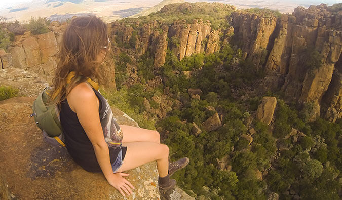 Kristin Addis sitting on a rock in South Africa with her legs dangling over the edge