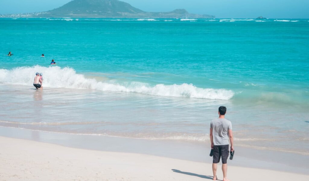 Nomadic Matt standing on a beach overlooking turquoise blue waters in Hawaii