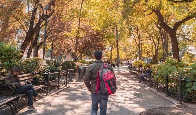 Nomadic Matt walking down a path in Central Park wearing a backpack