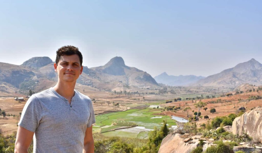 Nomadic Matt posing for a photo in Africa with a wide, sweeping valley in the distance behind him