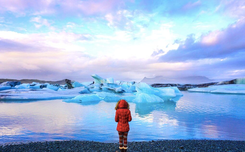 solo female traveler in a read coat at the Glacier Lagoon in Iceland