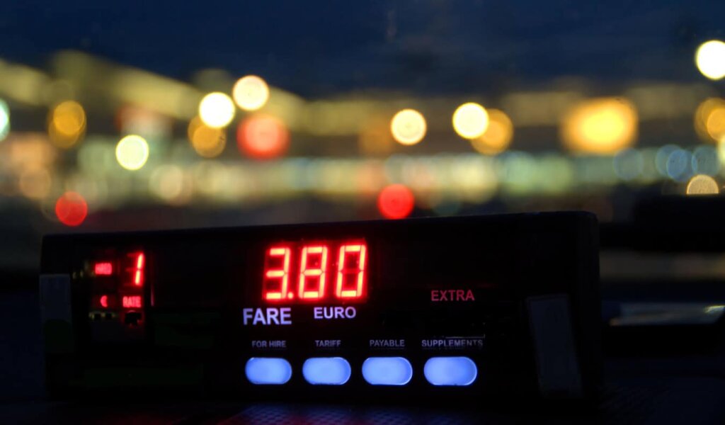 A taxi meter in a taxi cab in Europe on a dark and rainy night