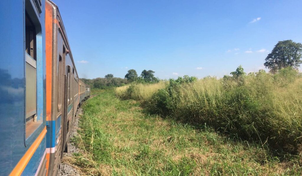 A train pass through a field in Isaan, Thailand