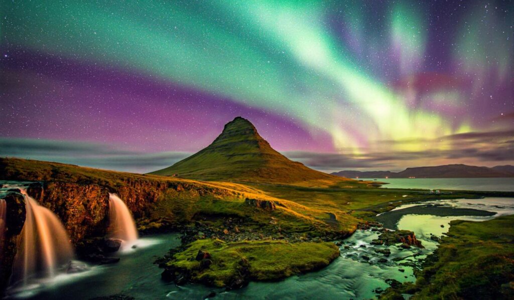 The northern lights in Iceland at night over a lone mountain in the snwoy landscape