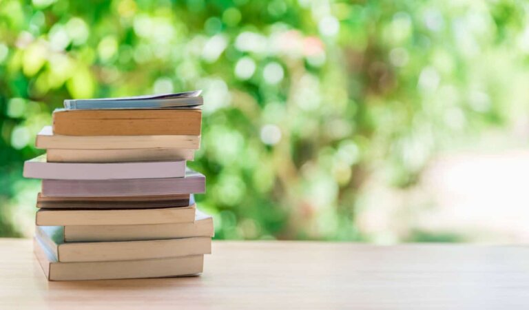 A stack of books on a table outside on a sunny day