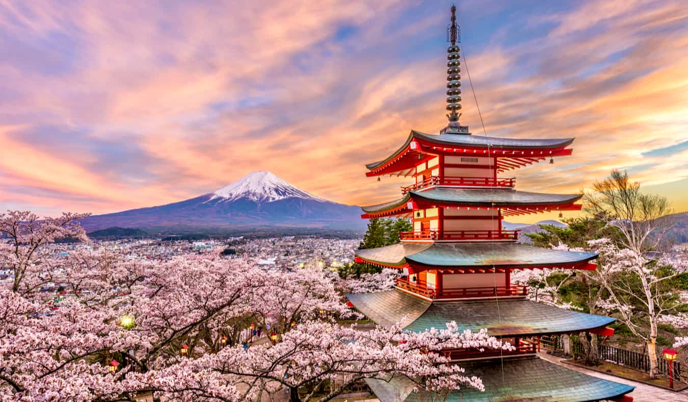 A view of a pagoda and Mount Fuji at sunset.