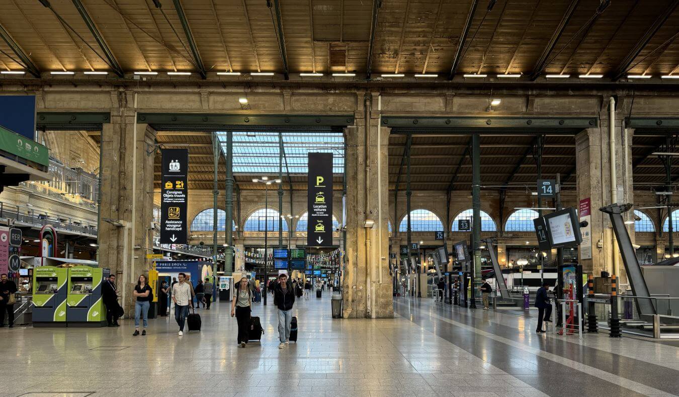 People rolling luggage through a train station in France