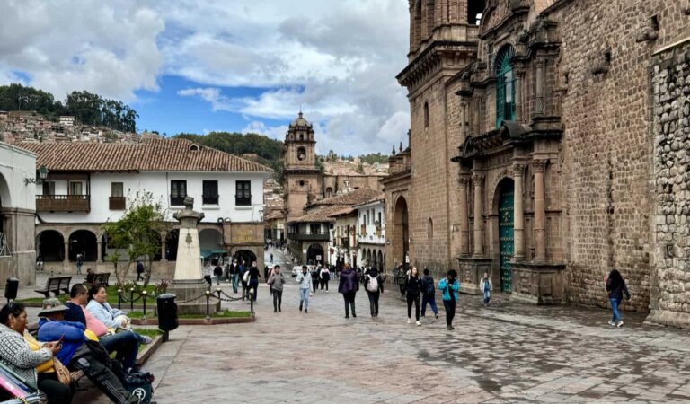 A historic plaza full of tourists and locals in sunny Cusco, Peru