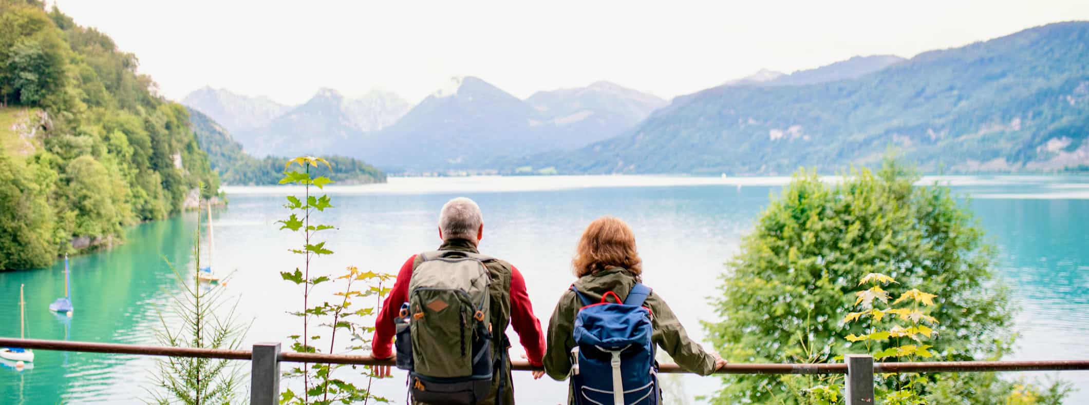 A senior traveling couple looking out over a lake while abroad